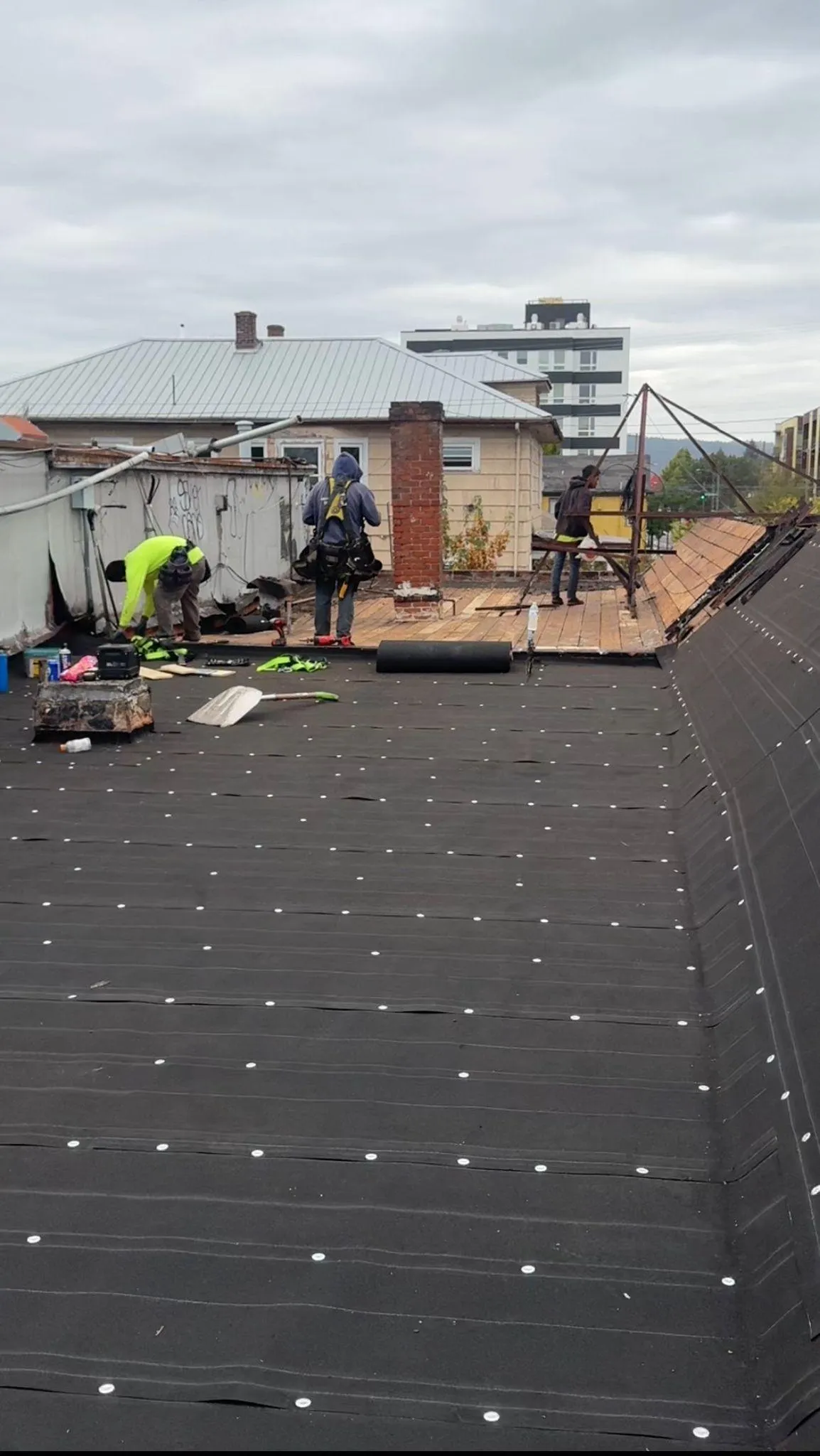 Roofing workers on a house with equipment and tools